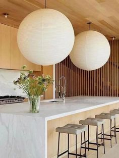 a kitchen with marble counter tops and stools in front of two large white balls hanging from the ceiling