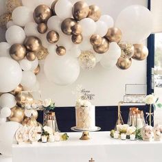 a table topped with white and gold balloons