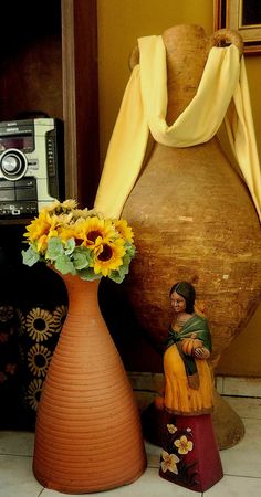 a vase with sunflowers in it next to a small statue on a table