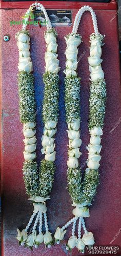 two white flowers are attached to the side of a vending machine that is decorated with beads and pearls