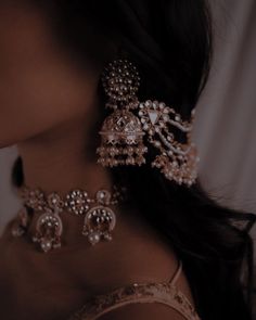 a close up view of a woman's neck wearing earrings and necklaces with pearls on them