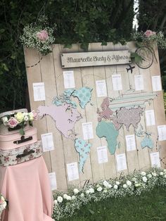 a wooden sign that has a world map on it and flowers around the board with names