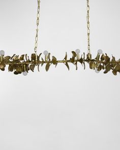 a gold leaf chandelier hanging from a chain with three lights on each end