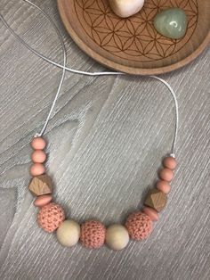 the necklace is made with wood beads and other items on a wooden tray next to a bowl