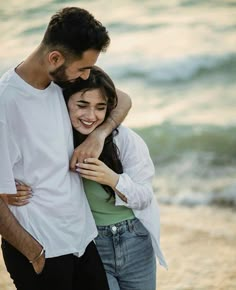 two people hugging each other on the beach