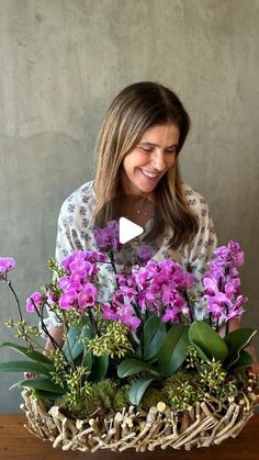 a woman holding a basket with purple flowers in it