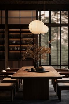 a dining room table with chairs and a vase on the table in front of large windows