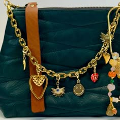 a green purse with gold chains and charms on it