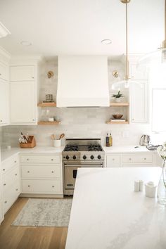 a kitchen with white cabinets and stainless steel stove top oven in the middle of the room