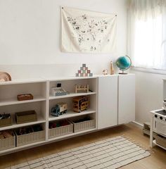 a living room with white furniture and an area rug on the floor that has various toys in it