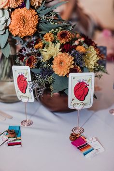 a vase filled with lots of flowers sitting on top of a table next to cards