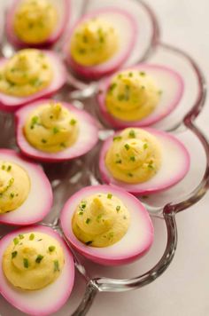 small deviled eggs with chives in them on a glass platter, ready to be eaten