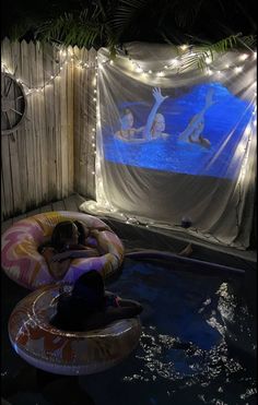 two people floating in an inflatable pool with lights on the wall behind them