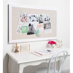 a white desk topped with a white chair next to a wall mounted art work area