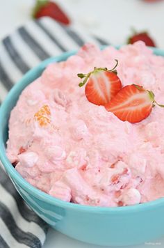 a blue bowl filled with strawberry fluff and topped with two strawberries