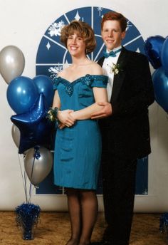 a man and woman standing next to each other in front of balloons