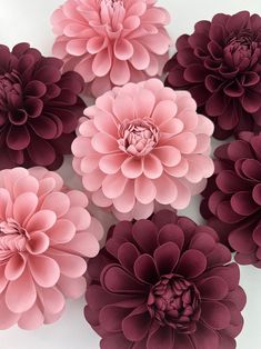 pink and purple paper flowers are arranged on a white surface, with one large flower in the center