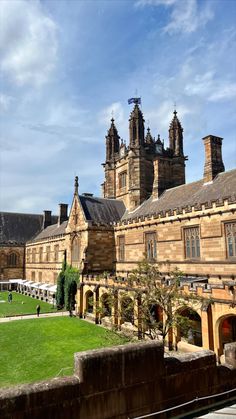 an old building with many windows and towers on it's sides, in front of a grassy field