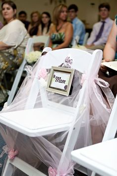 there are many people sitting in chairs with pink bows on them and one is holding a sign that says mum