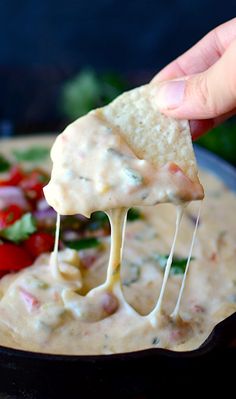 a tortilla chip being dipped with quesadilla sauce and garnished with fresh vegetables