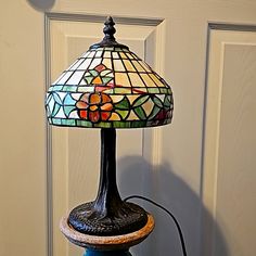 a stained glass lamp sitting on top of a blue table next to a white door