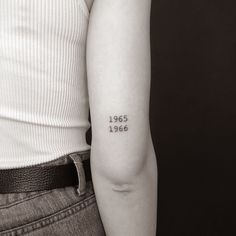 a woman with a tattoo on her arm that reads, 1965 - 2006 written in cursive letters