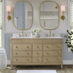 a bathroom vanity with two mirrors above it and flowers in vases on the counter