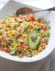 a white bowl filled with corn and avocado