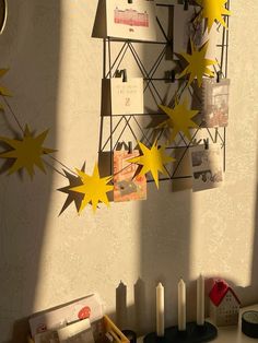 some yellow stars hanging from the side of a wall next to candles and other items