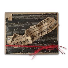 an old piece of music paper with red string attached to it and some sheet music on top