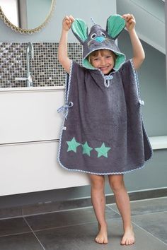 a little boy standing in front of a bathroom sink wearing a towel with an animal on it