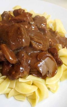 a white plate topped with pasta and meat covered in gravy on top of it