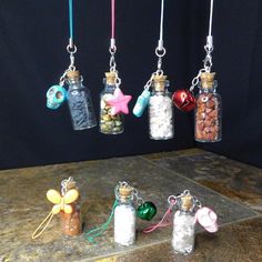 four glass bottles filled with different types of candy and candies hanging from chains on a table