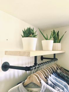 two potted plants are sitting on top of the clothes rack