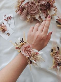 a woman's hand with flowers and feathers on her wrist, surrounded by other items