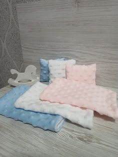 three blankets are laying next to each other on a wooden surface with a rocking horse