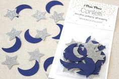 blue and silver stars and crescents are on the table next to a package of confetti