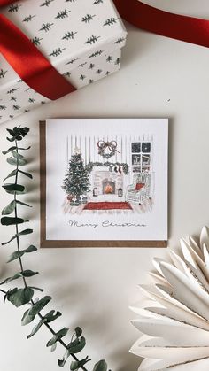 a christmas card with an image of a fireplace and tree on it next to a red ribbon