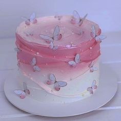 there is a pink and white cake with butterflies on it