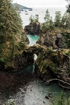 an arch in the rock with water and trees around it