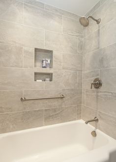 a white bath tub sitting inside of a bathroom next to a shower head and hand rail