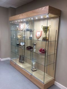 a glass display case with trophies and other items on it's sides in a room