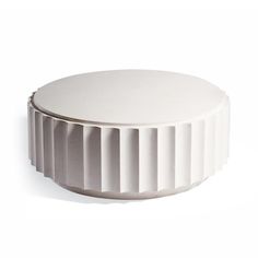 a white round object with pleated edges sitting on a white surface, against a white background