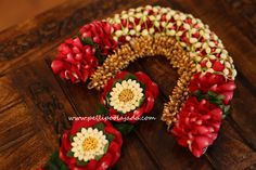 red and white flowers are arranged in the shape of a wreath on a wooden table