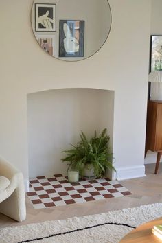 a living room with a potted plant on the floor and a mirror above it