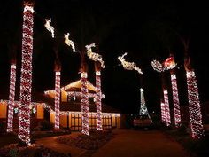 christmas lights are lit up in front of a house with santa's sleighs on it