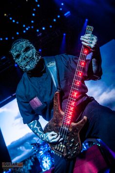 a man in black shirt holding up a guitar with red light on it's neck