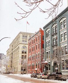 a snowy day in the city with cars parked on the side of the street and buildings