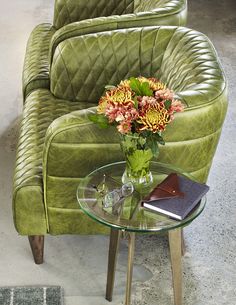 a green chair and table with flowers on it in front of a gray carpeted floor