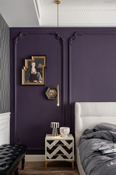 a bedroom painted in purple and white with a bed, side table, and pictures on the wall